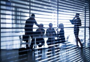 Image shot through open blinds of team meeting in an office