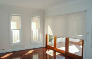 Half-closed white roller blinds on wooden windows & doors