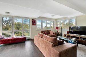 Brown sofa sitting in room with door & window shutters