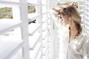 Blonde woman in white shirt standing near Fusion Plus shutters