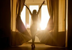 Woman opening curtains in morning