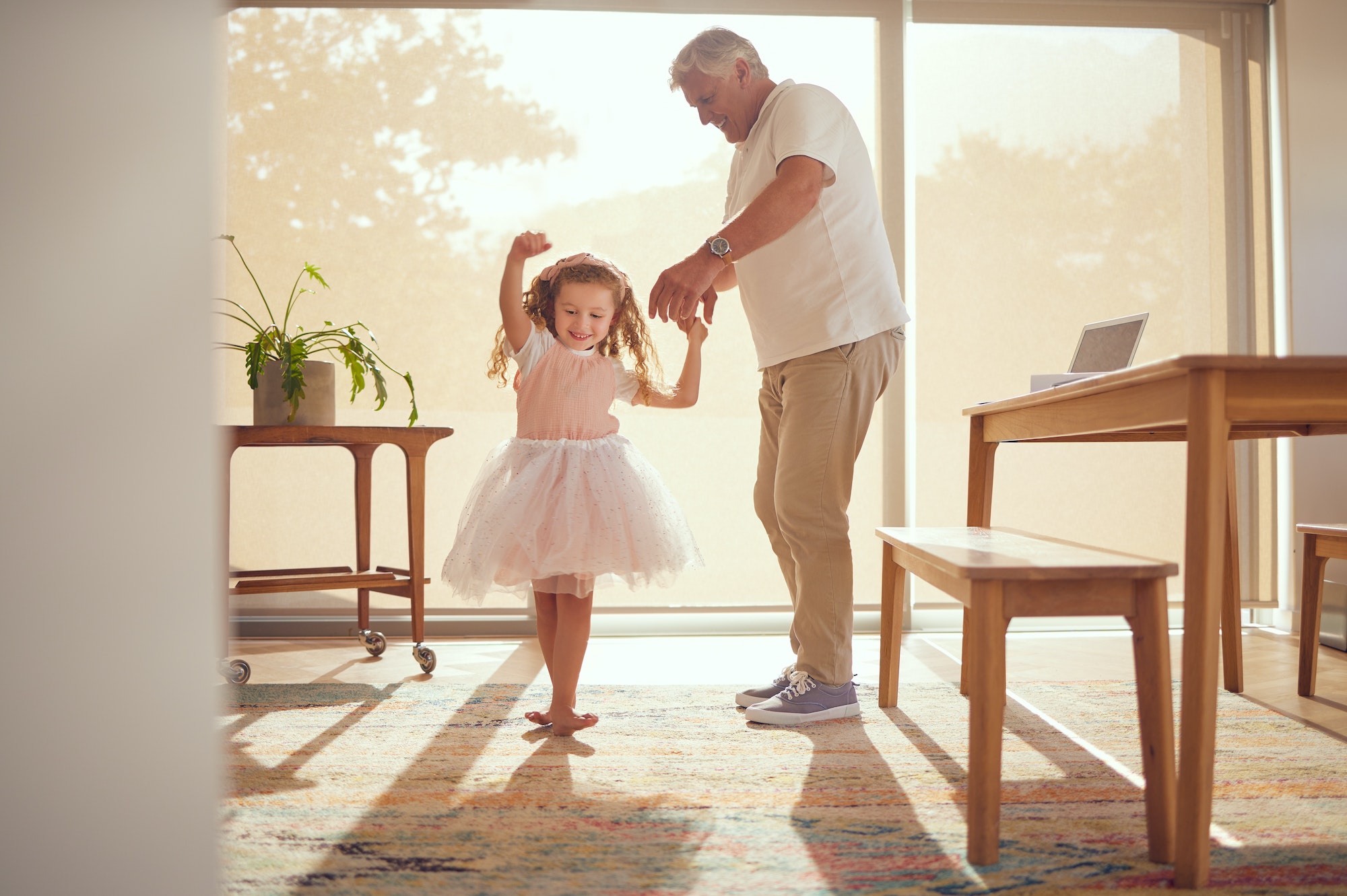 Family, young girl and grandfather dancing in living room together. Grandparent and grandchild in f